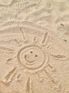 a smiley face drawn in the sand on a beach