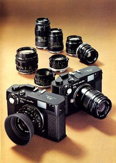 an old camera with many different lens types around it on a brown background, and several smaller ones in the foreground