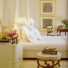 a white bed sitting in a bedroom next to a table with flowers on top of it