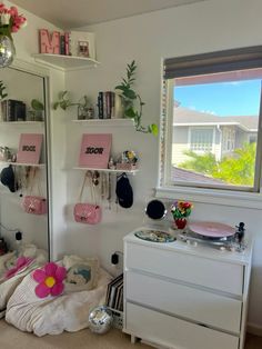 a bedroom with white walls and pink accessories on the wall, along with other items