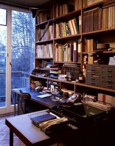 a home office with lots of books on the shelves and a desk in front of a large window