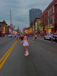 a woman in a white dress is dancing on the street