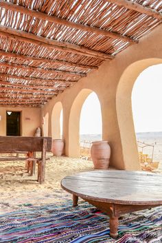 the inside of an adobe style building with round wooden tables and potted planters