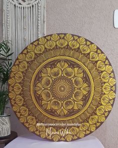 a decorative wooden plate sitting on top of a table next to a potted plant