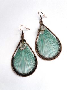 two pairs of earrings are shown on a white surface