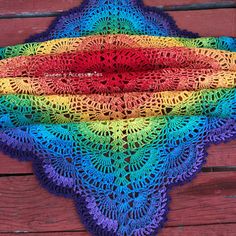 a multicolored crocheted shawl on a wooden surface