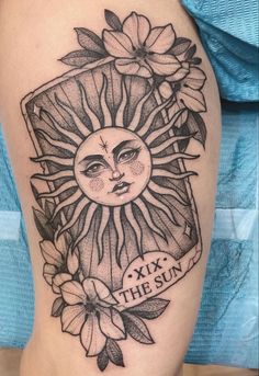 a sun tattoo on the thigh with flowers and leaves around it's face, as well as a banner that says six to the sun