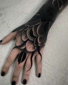 a woman's hand with black and white tattoos on it, which is decorated with flowers