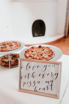 two personal pizzas are on display at a wedding reception in front of a sign that says i love you