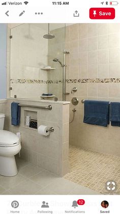 a white toilet sitting next to a walk in shower under a bathroom mirror with blue towels on it