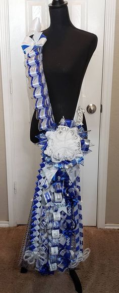 a mannequin with blue and white ribbons on it's torso, standing in front of a door