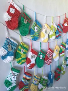 crocheted christmas stockings hanging on a clothesline with buttons and numbers attached to them