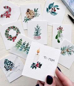 a person holding a card with christmas decorations on it and the words to mom written in front of them