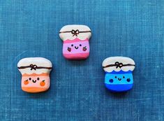 three painted rocks sitting on top of a blue surface