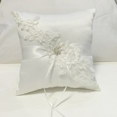 a white pillow with a flower on the side and a ribbon tied to it's back