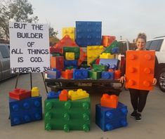 a woman standing next to a pile of legos in front of a sign that says, but the builder of all things is god