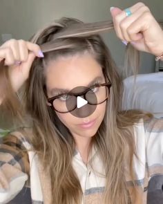 a woman with long hair and glasses is straightening her hair in front of the camera