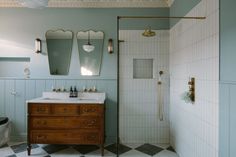 a bathroom with blue walls and white tile flooring, two mirrors on the wall