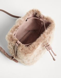 Fleecy shearling bucket bag The classic bucket style is presented in a very soft, precious version in this new Fleecy shearling bucket bag. The refined material’s plush, full effect enhances the accessory’s relaxed lines with a sophisticated touch. The leather handles and drawstring introduce a texture contrast and represent functional details that are perfect for a little girl’s daily adventures. Leather Bags With Plush Lining For Everyday Use, Leather Bag With Faux Fur Lining, Fur Clutch Bag, Fuzzy Bag, Winter Purses, Texture Contrast, Winter Handbags, Fur Clutch, Crocheted Bags