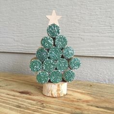 a small green christmas tree made out of cookies on top of a wooden table next to a white wall