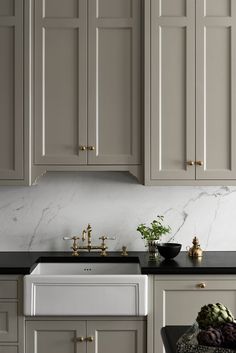 a kitchen with white cabinets and black counter tops, gold pulls on the faucet