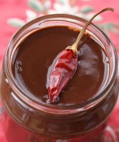 a jar filled with chocolate pudding and a red chili pepper on the top of it