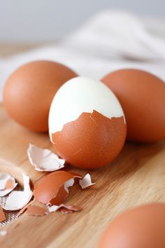 three eggs on a wooden cutting board with one broken egg in the middle and another cracked