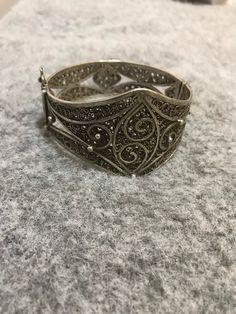 A beautiful antique Moroccan berber silver bracelet with Morocco silver marks, silver filigree, with a sliding pin closure . Handmade from 80 percent silver. The filigree is in good condition and the bracelet functions as it should. It is in general in good vintage condition. Width of large side : 4,2cm Inner diameter : 6cm Weight : 41.4g Bohemian Filigree Bangle Bracelet, Bohemian Bangle Bracelet With Filigree, Bohemian Silver Filigree Bracelets, Antique Silver Bracelet With Intricate Design, Antique Sterling Silver Bracelet With Intricate Design, Bohemian Silver Filigree Ring With Intricate Design, Ornate Sterling Silver Filigree Bracelet, Silver Bohemian Filigree Ring With Intricate Design, Silver Filigree Ring With Intricate Design In Bohemian Style