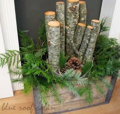 logs are stacked on top of each other in the center of a box filled with greenery and pine cones