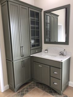 a bathroom with gray cabinets and white counter tops