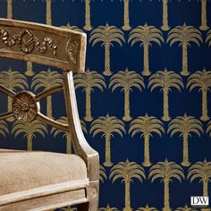 a chair sitting in front of a blue wallpaper with gold palm trees on it