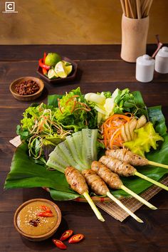 a table topped with lots of different types of food on top of green leafy leaves