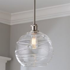 a clear glass light fixture hanging from a ceiling in a room with gray walls and white trim