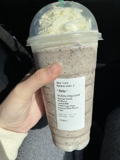 a person holding up a drink with whipped cream on top