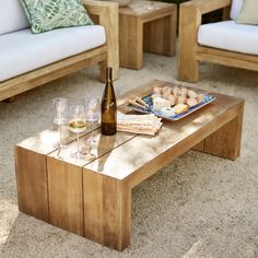 a wooden table topped with wine glasses next to two couches and a coffee table