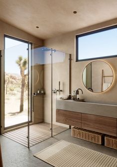 a bathroom with a sink, shower and large window overlooking the desert outside at night