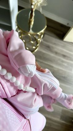 a doll is wearing a pink outfit with white beads on it's head and hands