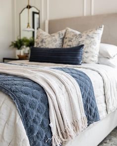 a bed with blue and white blankets on it's headboard in a bedroom