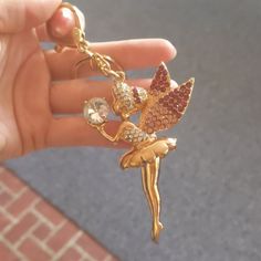 a person holding onto a gold charm with a flower on it's side and a crystal bead in the middle