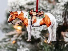 a brown and white horse ornament hanging from a christmas tree