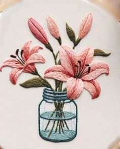 a glass jar filled with pink flowers on top of a table