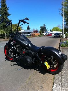 a black motorcycle parked on the side of a road next to a parking lot with cars in the background