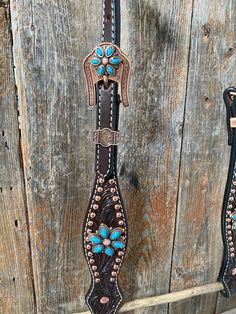 two brown and blue western style belts hanging on a wooden wall