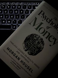 a book sitting on top of a laptop computer next to a keyboard with the words psychic money written on it