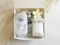 a white box with some items in it that include soap, lotion and flowers