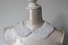 Handmade collar necklace with white and clear pearls in different sizes.  Peter pan collar style. Ribbon tied on the back. Adjustable to every neck size. Every single bead is handsewn.  Collar gives a chic touch to simple dresses and blouses.  One size. Handmade item. Wonderful gift for women or female friends. Please check out other items in my shop. You can find there collars in different shapes, colors and materials. Great to wear everyday and also for special occasions. Elegant White Lace Collar, White Bib Necklaces For Wedding, White Bib Necklace For Wedding, White Pearl Bib Necklace For Wedding, Elegant White Pearl Bib Necklace, White Pearl Wedding Bib Necklace, Elegant White Bib Necklace For Wedding, Elegant Bib Necklace With Round Beads For Wedding, Elegant White Bib Necklace Choker