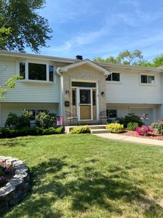 a house with landscaping in front of it and flowers on the lawn next to it