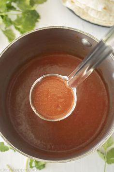 a spoon in a pot filled with sauce and garnished with cilantro