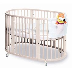 a white baby crib with a stuffed animal on it