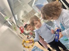 two young children playing with toys in an indoor play area, while another child looks on